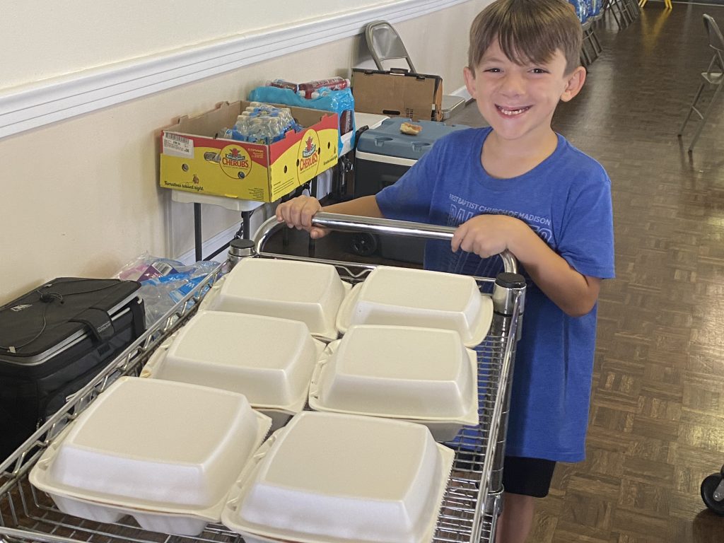 young boy distributes meals from cart